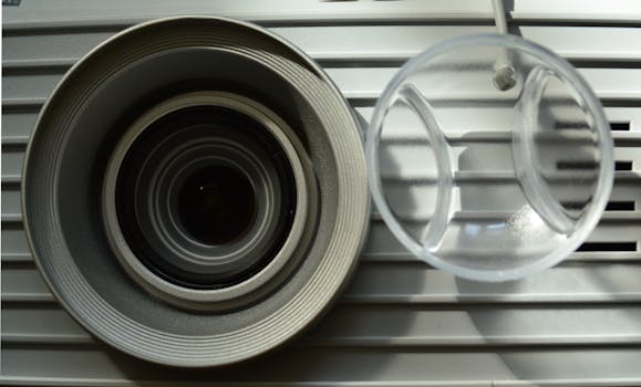Detailed close-up of a modern projector lens with metallic elements and reflections.