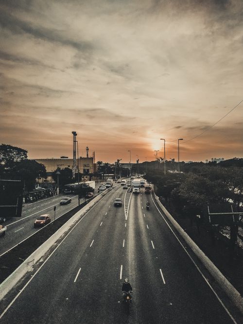 Free A vibrant sunset over a busy city highway with vehicles driving in both directions, depicting daily commute. Stock Photo