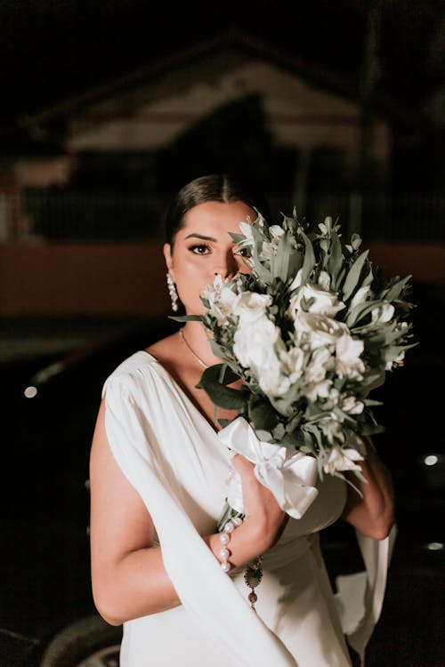 A bride holding a bouquet in front of a car