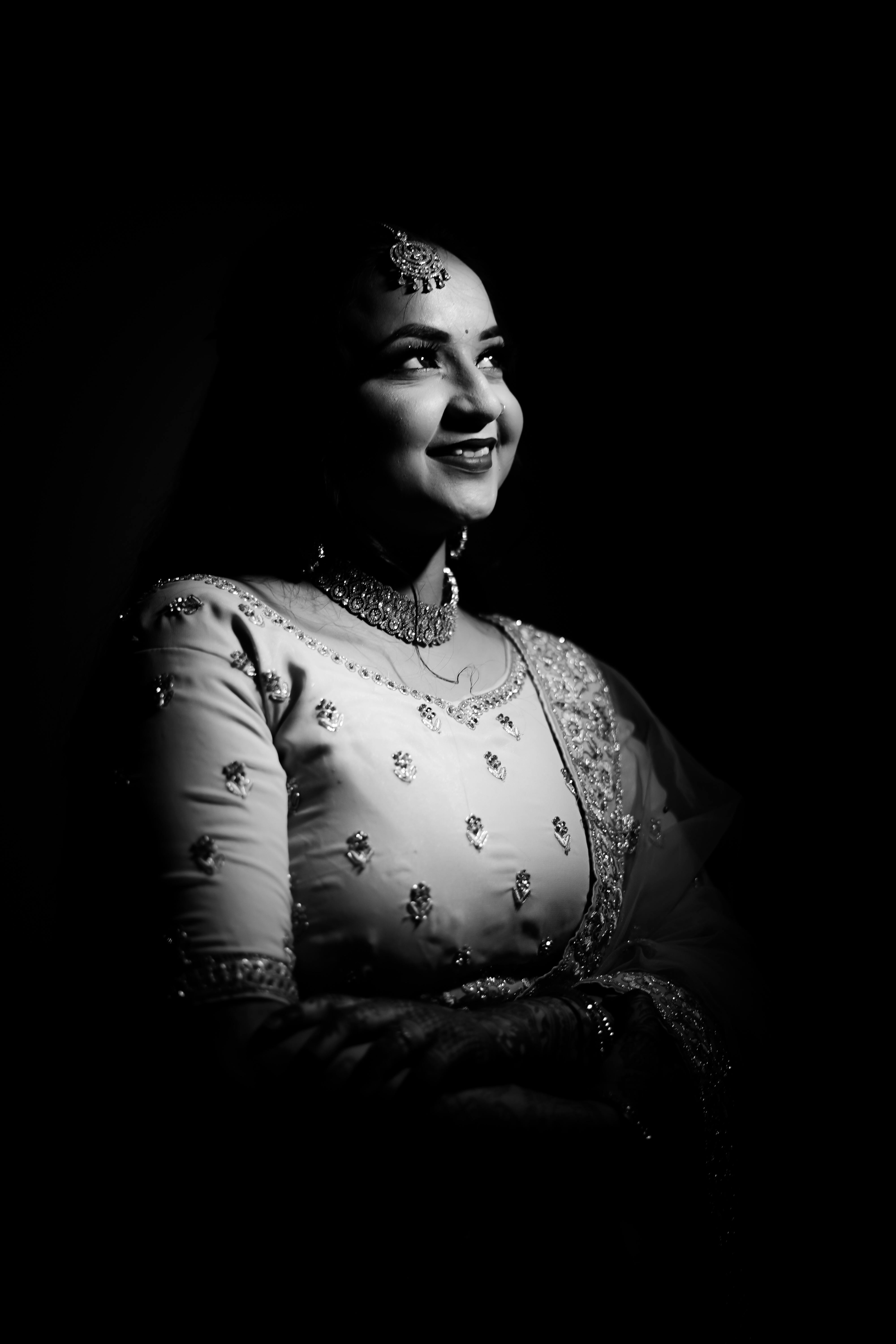 Black and white portrait of a woman in elegant traditional attire, smiling gracefully.