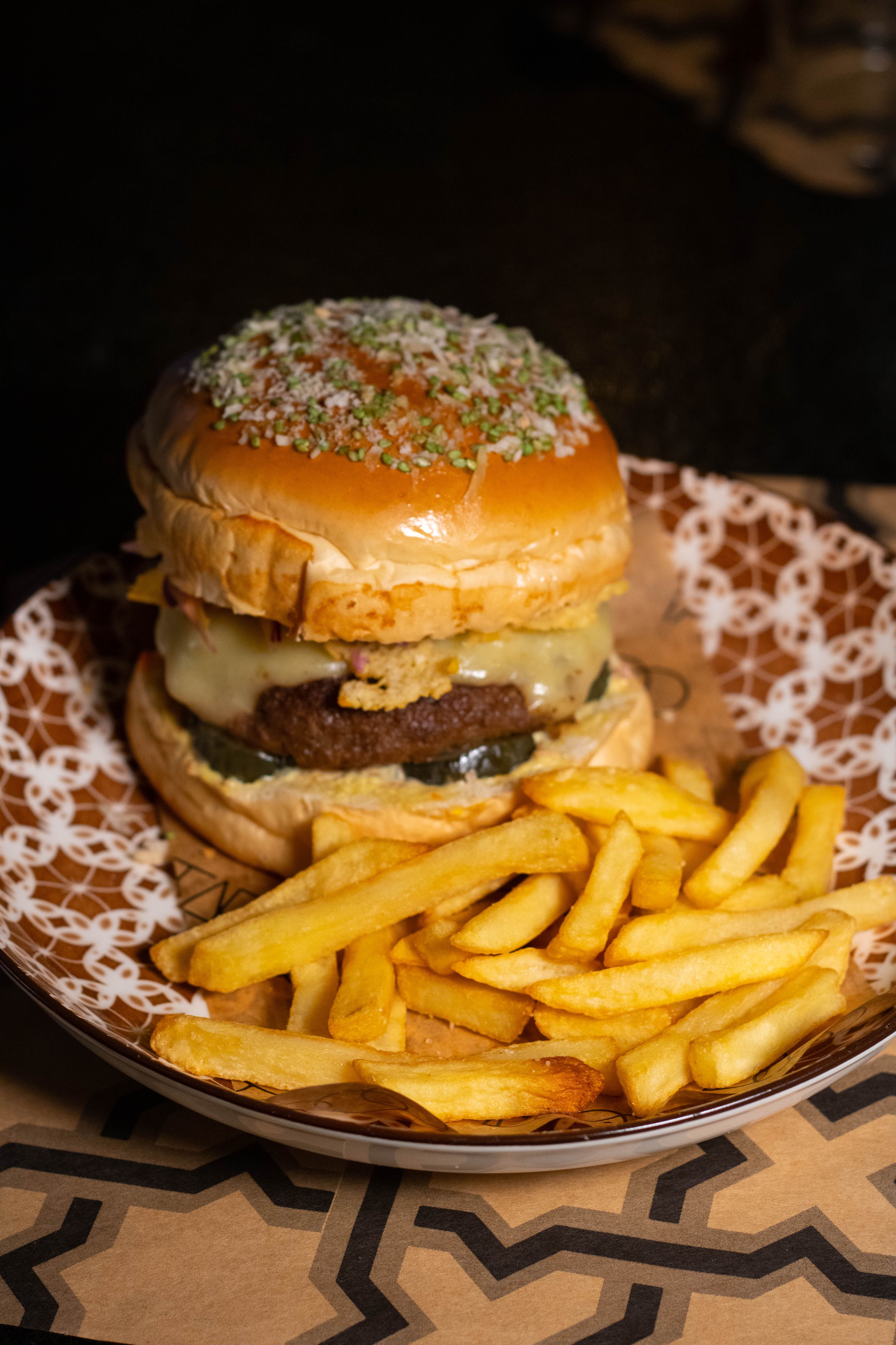 Delicious gourmet beef burger with cheese and crispy fries on a decorative plate.