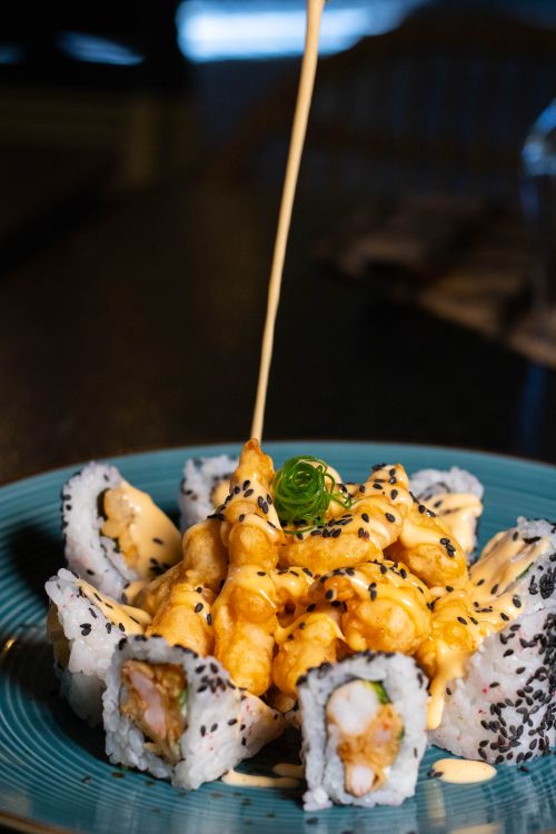 Free Close-up of sushi rolls topped with crispy shrimp and creamy sauce, ideal for food lovers. Stock Photo