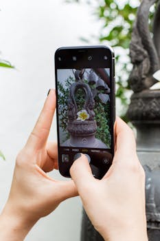 一个人在户外用智能手机拍摄花园雕塑，展示手机摄影