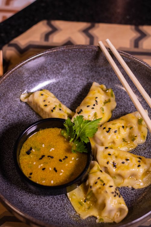 Free Close-up of gourmet dumplings served with sauce and chopsticks. Stock Photo