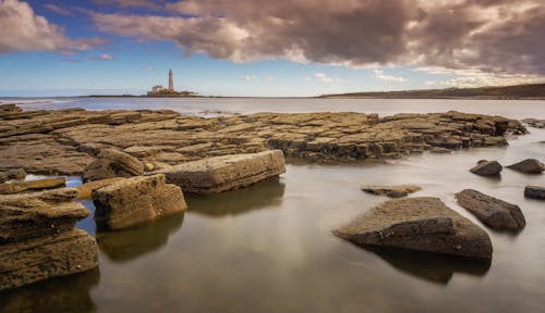 A lighthouse sits on a rocky shoreline