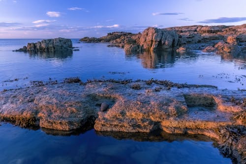 A rocky shore with blue water and rocks