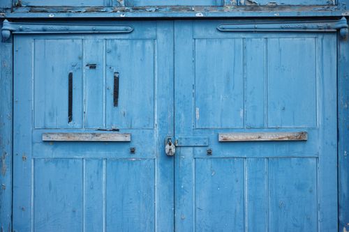 Free A close-up of rustic blue wooden double doors, securely padlocked, showcasing aged textures. Stock Photo