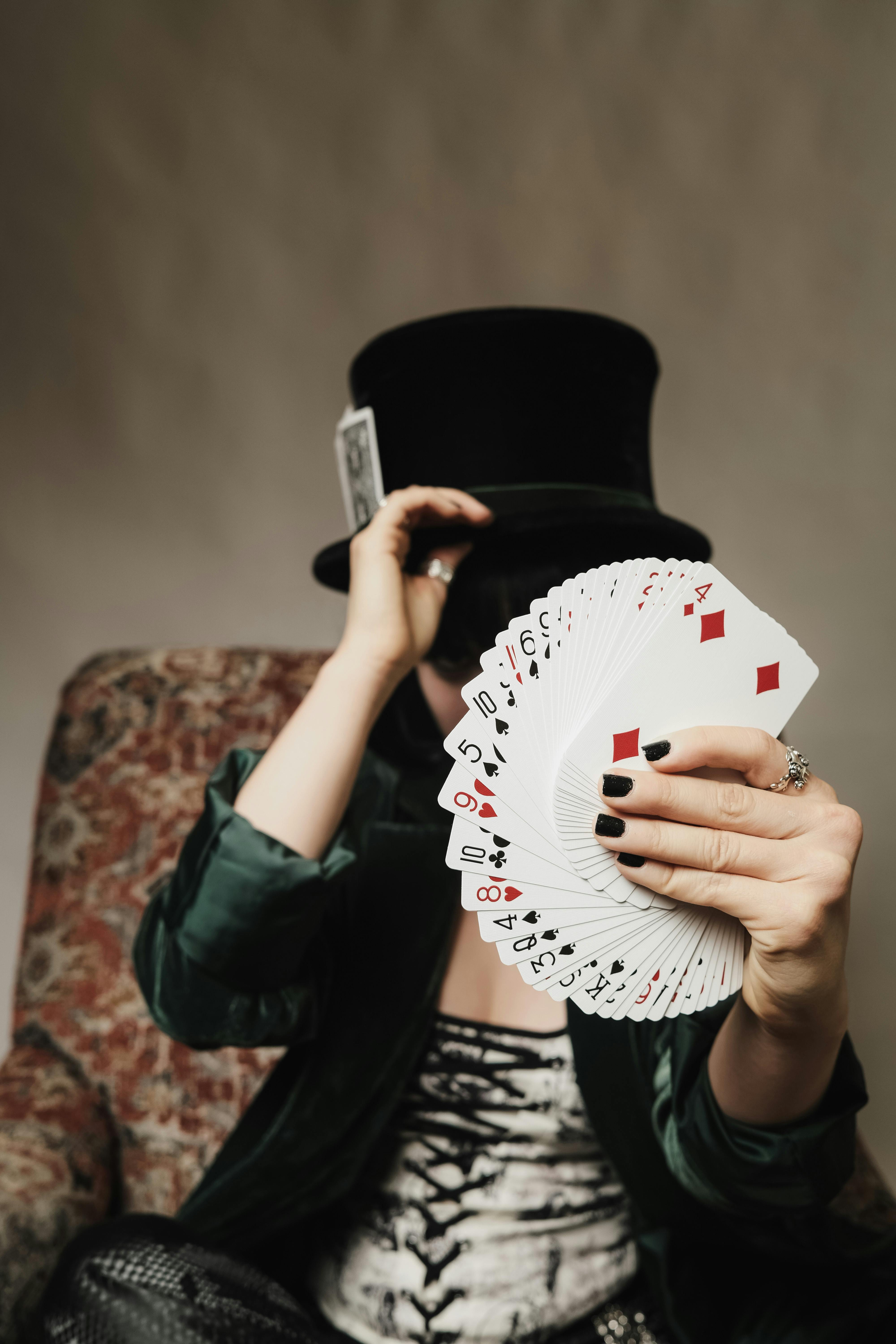 person in a top hat holding playing cards