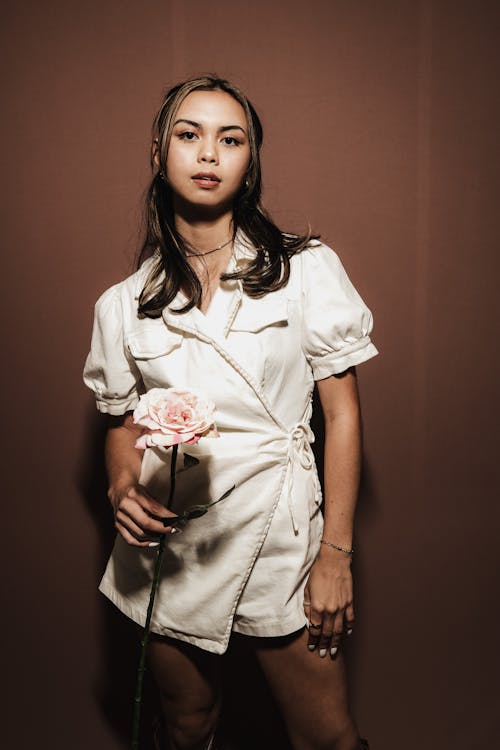 Gratis stockfoto met Aziatische vrouw, bloem, bruine achtergrond