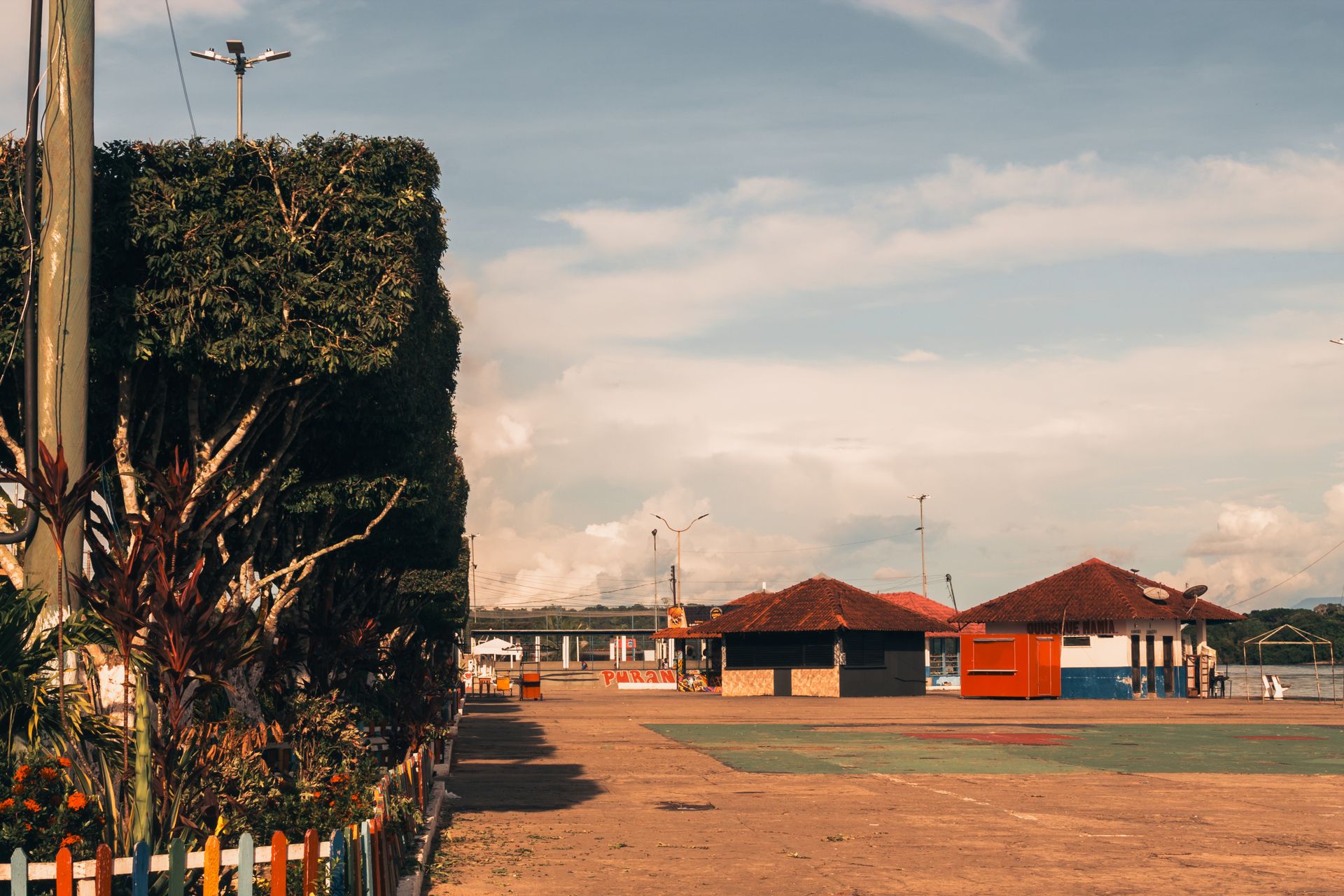 Empty urban square in São Gabriel da Cachoeira, Brazil, with trees and huts.