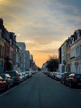 日落时分，里尔一条平静的城市街道两旁停满了汽车，并坐落着历史建筑
