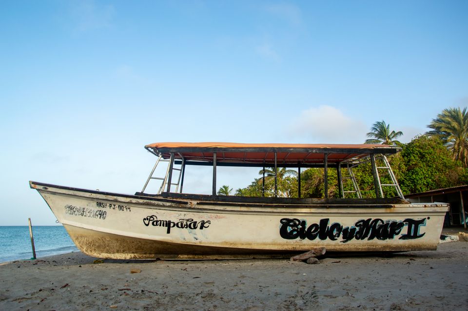 Weathered wooden tour boat with hand-painted name beached on sand