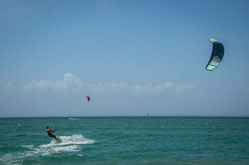 Free A man engaged in thrilling kitesurfing on a sunny day with clear skies and calm sea. Stock Photo