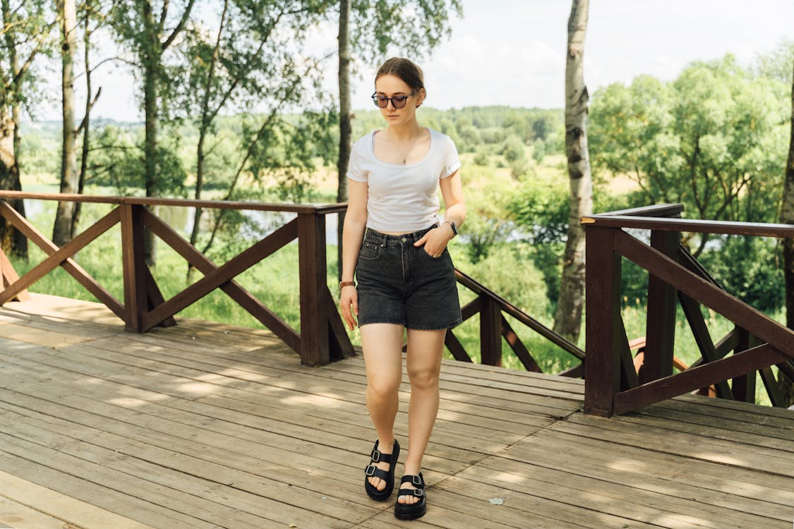 Woman in black shorts and white t - shirt standing on wooden deck
