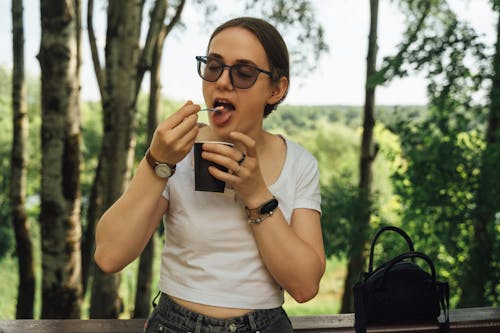 A woman eating a cup of coffee in the woods