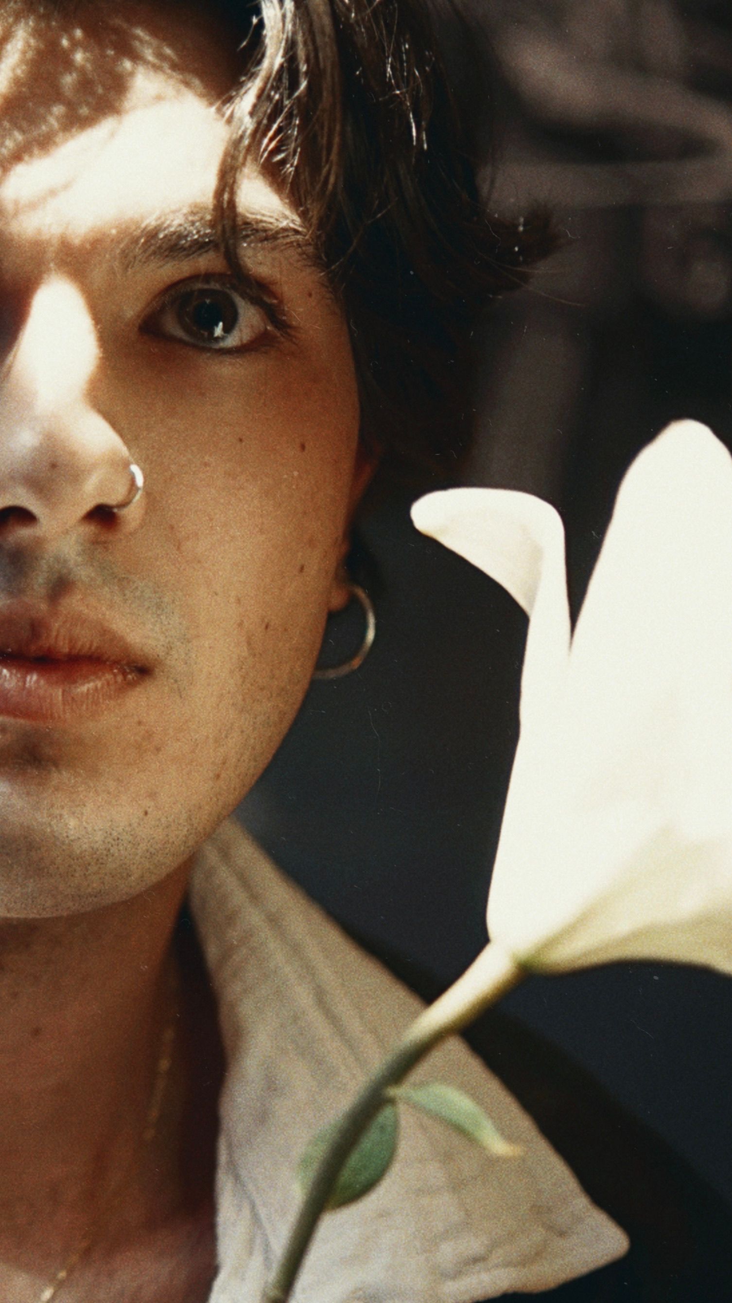Artistic portrait of a man with a lily flower, featuring soft focus and dramatic lighting.
