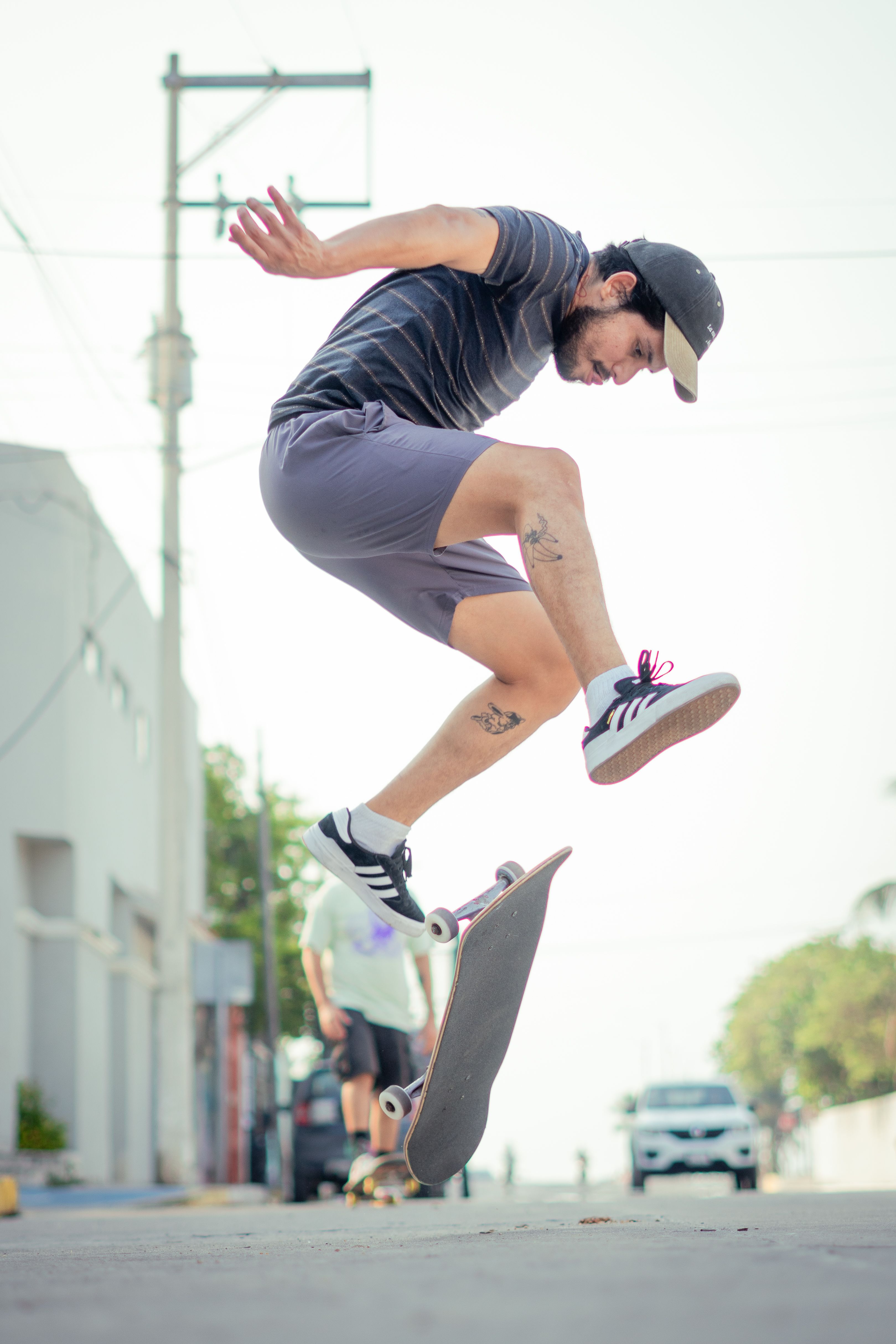 A skilled skateboarder executes a mid-air trick on a sunny city street.. skilled, skateboarder, executes