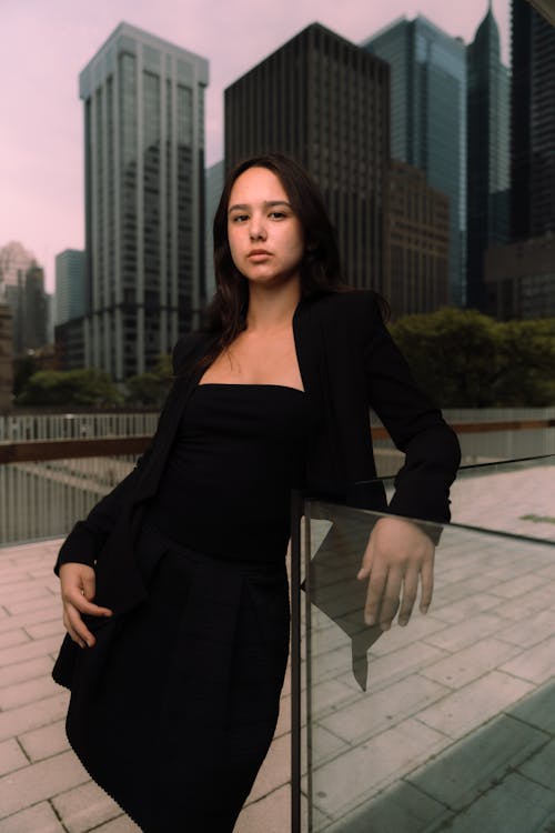 Free A woman in a black dress posing in front of a city skyline Stock Photo