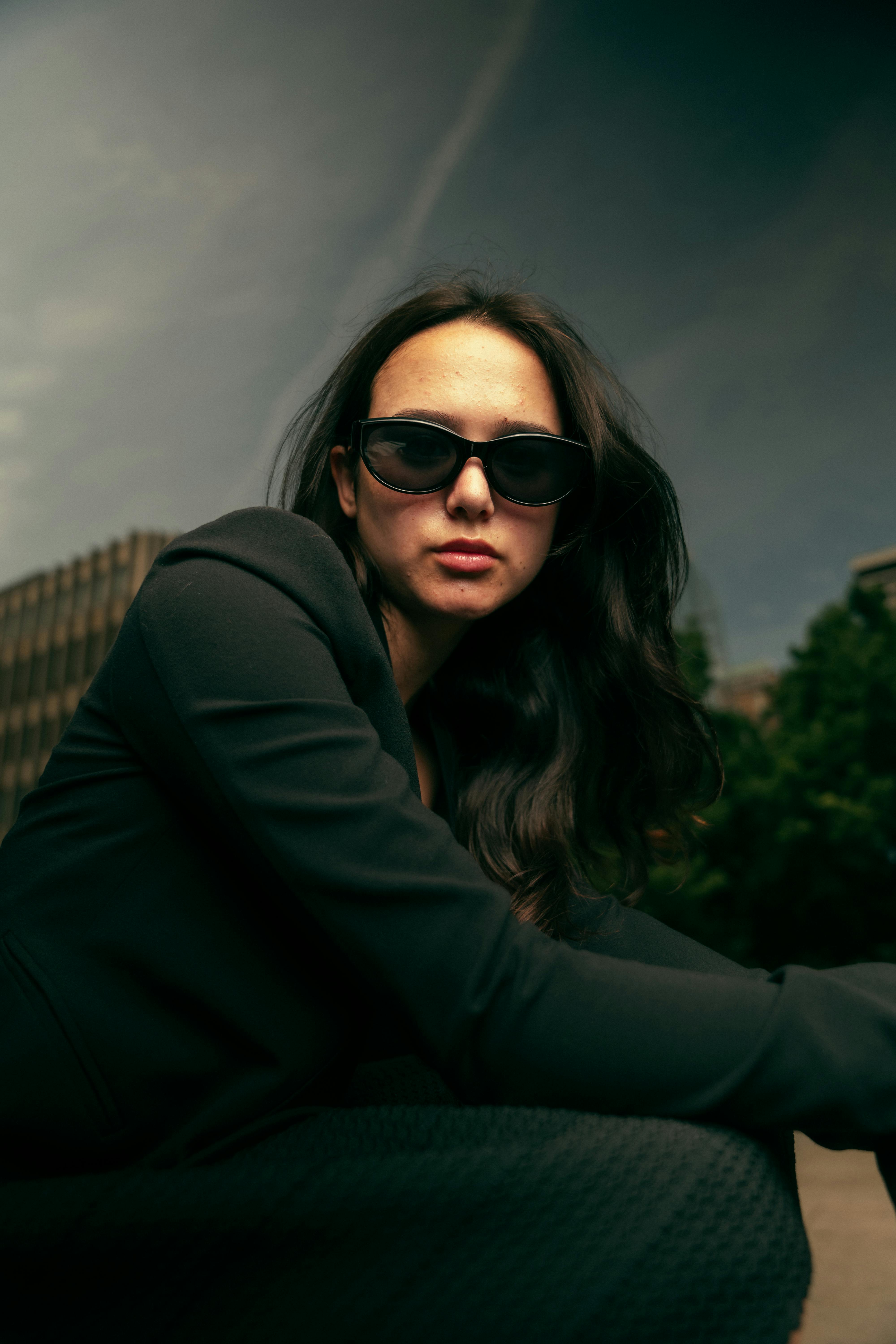 a woman in sunglasses sitting on a bench