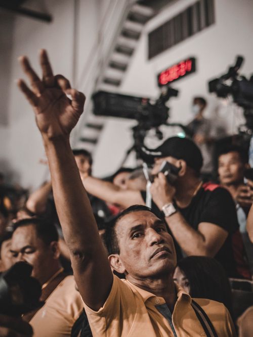 Free A man raises his hand in a crowd during an event in Bangkok, Thailand, with cameras in the background. Stock Photo
