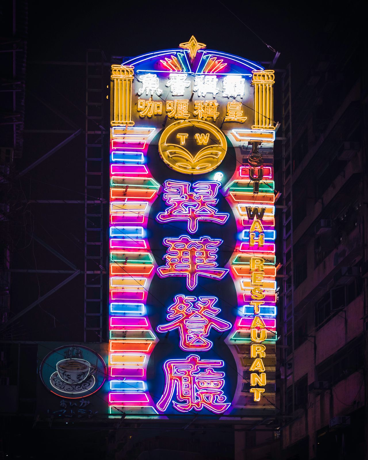 Bright neon sign of Tsui Wah Restaurant glowing in Hong Kong's urban nightscape.