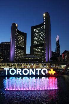 Stunning evening view of Toronto City Hall with illuminated fountain and iconic sign.