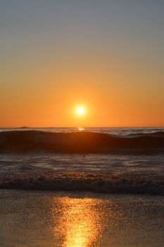 A breathtaking view of the setting sun casting vibrant reflections over ocean waves.