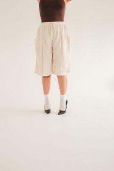 Model displays fashion contrast with elegant heels and casual shorts.