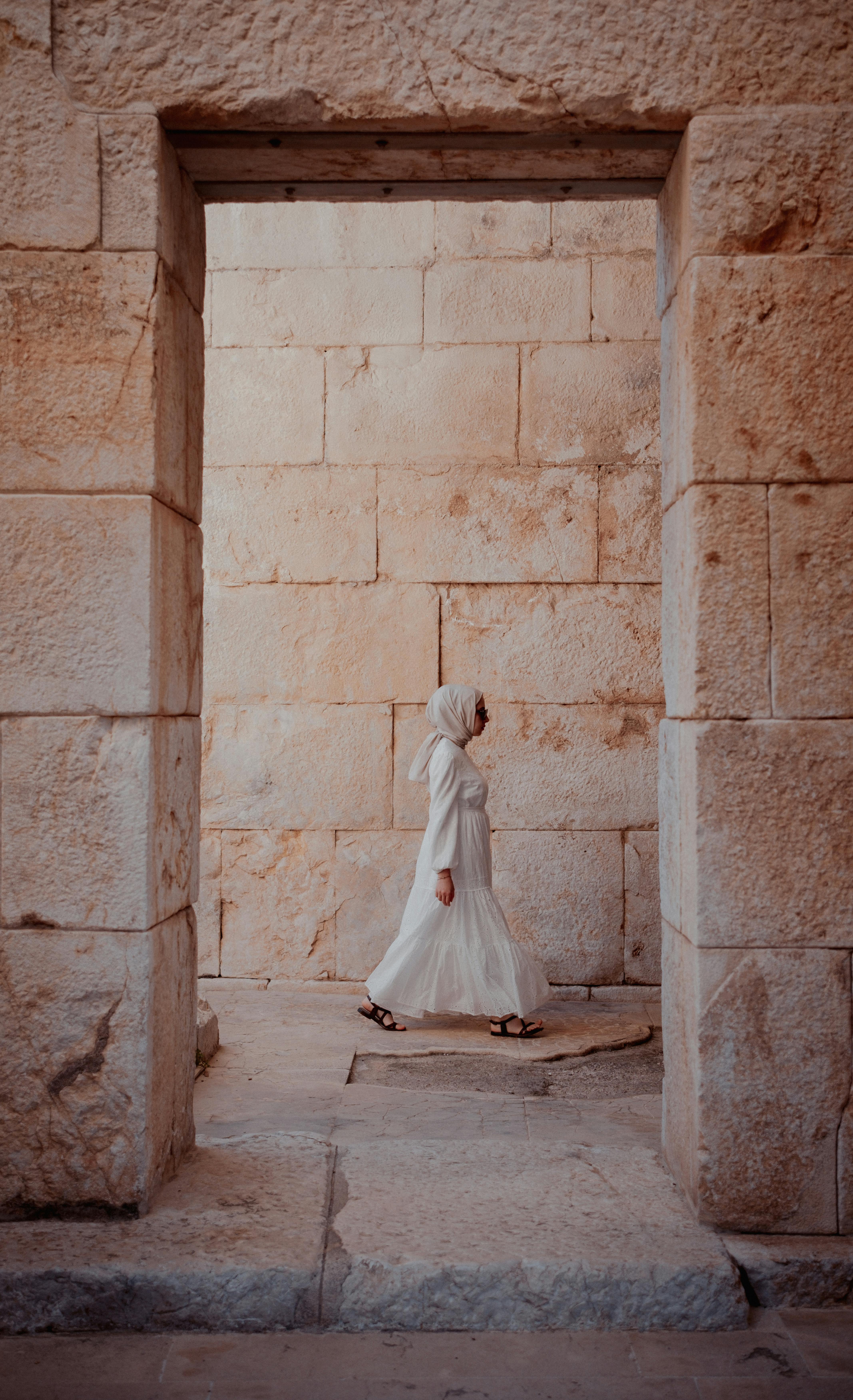 tourist in white dress in the doorway of ancient ruins