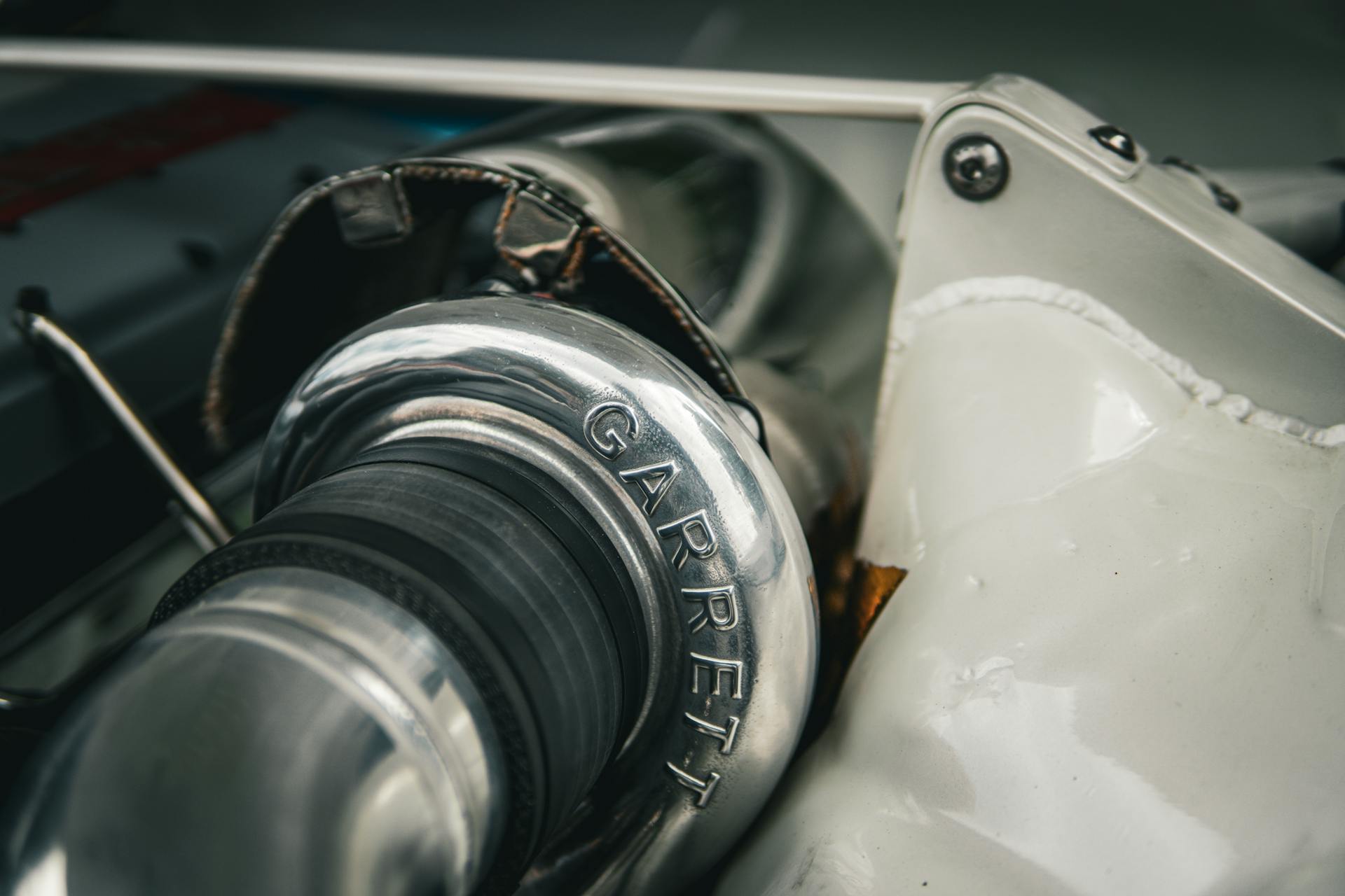 Detailed macro shot of a silver Garrett turbocharger part in an automotive setting.