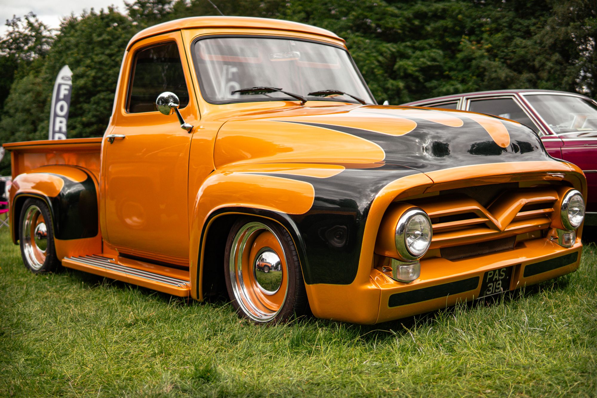 A classic Ford pickup on grass at an outdoor car show best matches the community classic car show setting described.