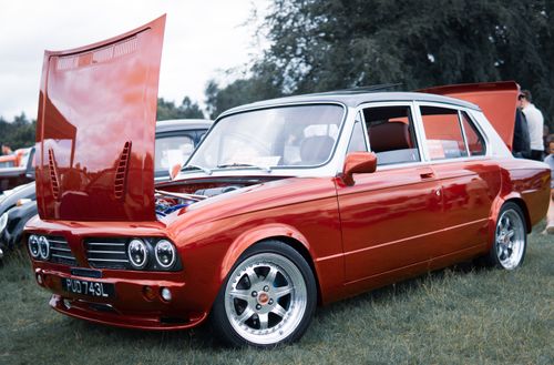 Free A classic red car with its hood open, displayed at an outdoor auto show. Stock Photo