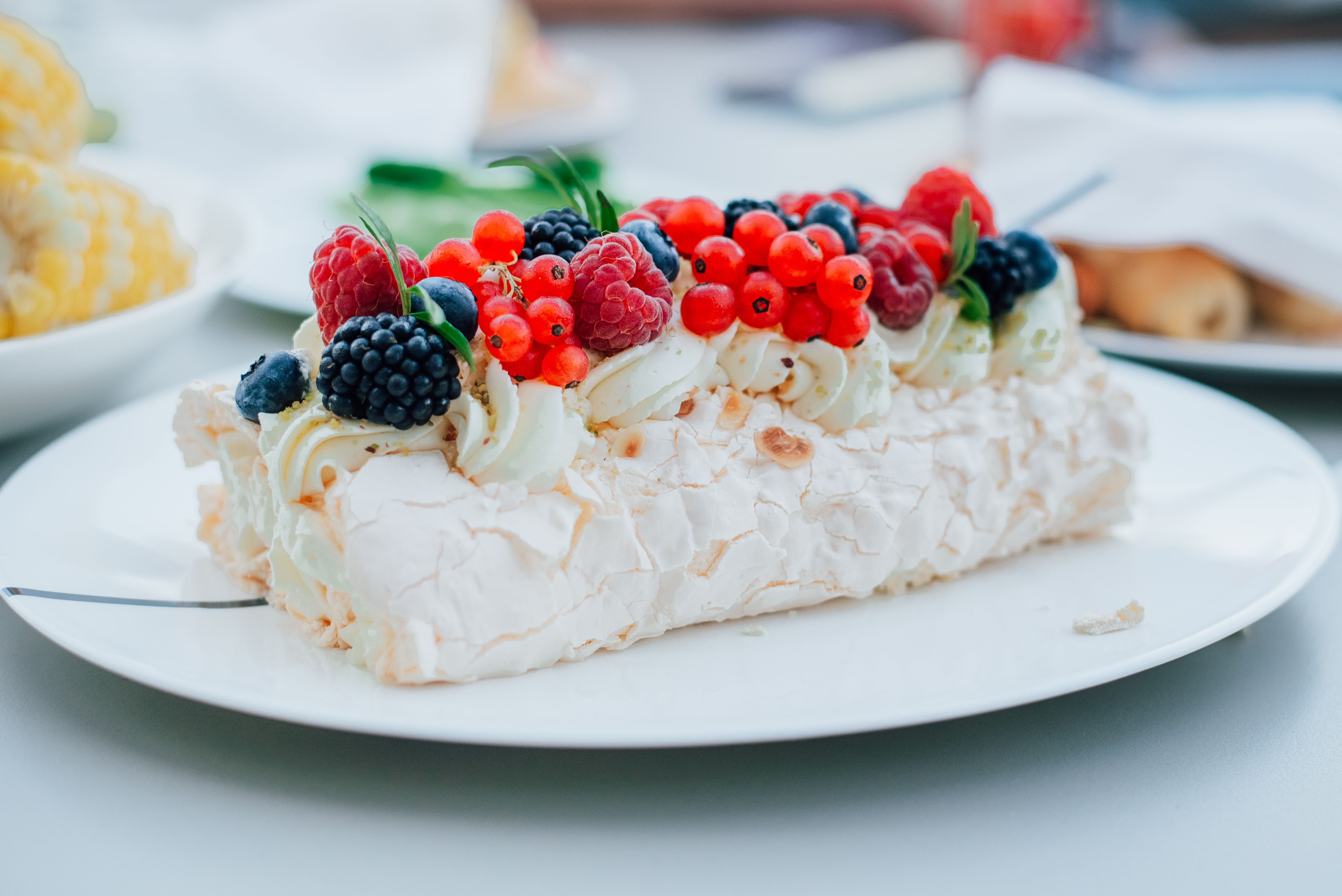 Close-up of a meringue cake topped with fresh berries including raspberries, blackberries, and currants.