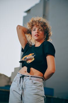 一位卷发的年轻女子在户外以休闲时尚的姿势摆拍