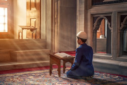 Photo of a Person Kneeling in Front of Book