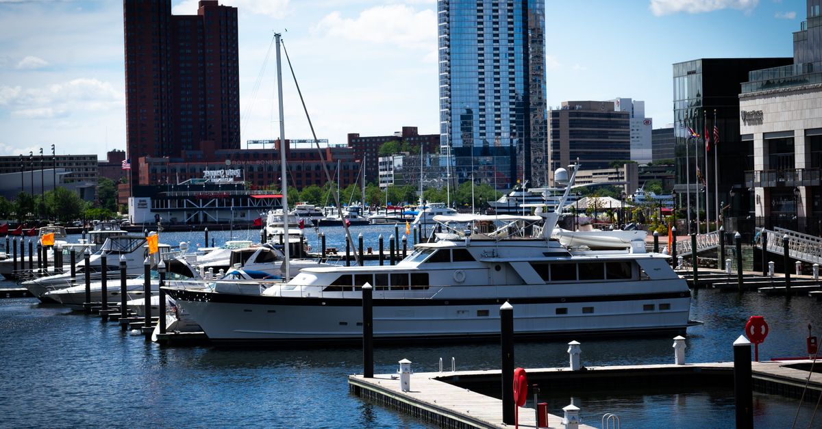 A bustling urban marina with yachts and modern skyscrapers on a sunny day.