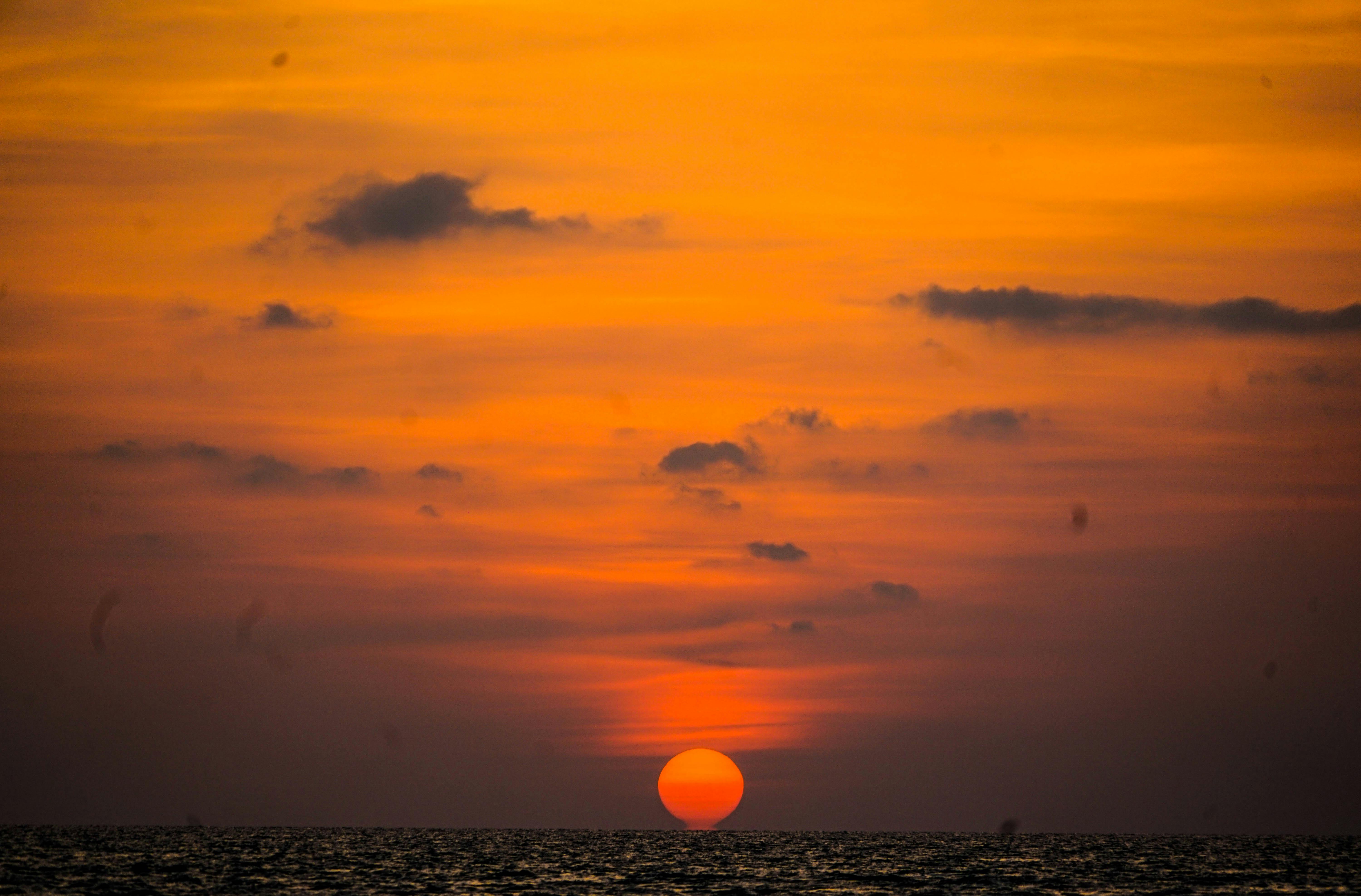 太阳沉入海洋，天空布满戏剧性的云层，呈现出充满活力的橙色，景象令人惊叹