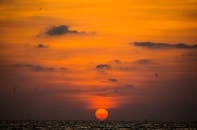 太阳沉入海洋，天空布满戏剧性的云层，呈现出充满活力的橙色，景象令人惊叹