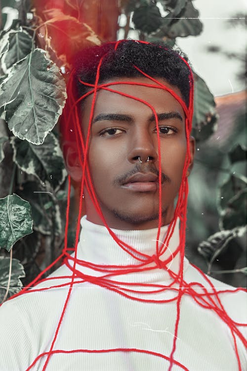 그의 머리와 가슴에 빨간 끈이있는 흰색 터틀넥 티셔츠에있는 남자의 초상 사진