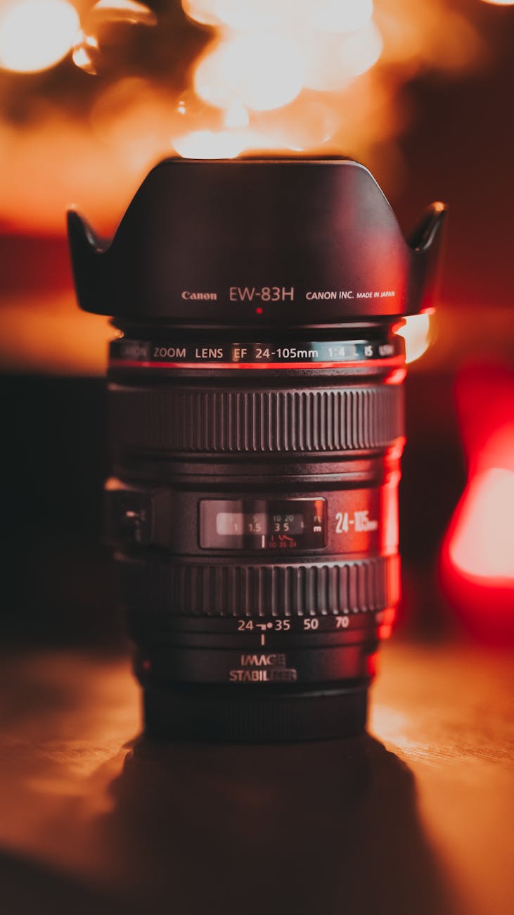 Close-up of a Canon camera lens with a warm bokeh background, showcasing its sleek design and optical detail.