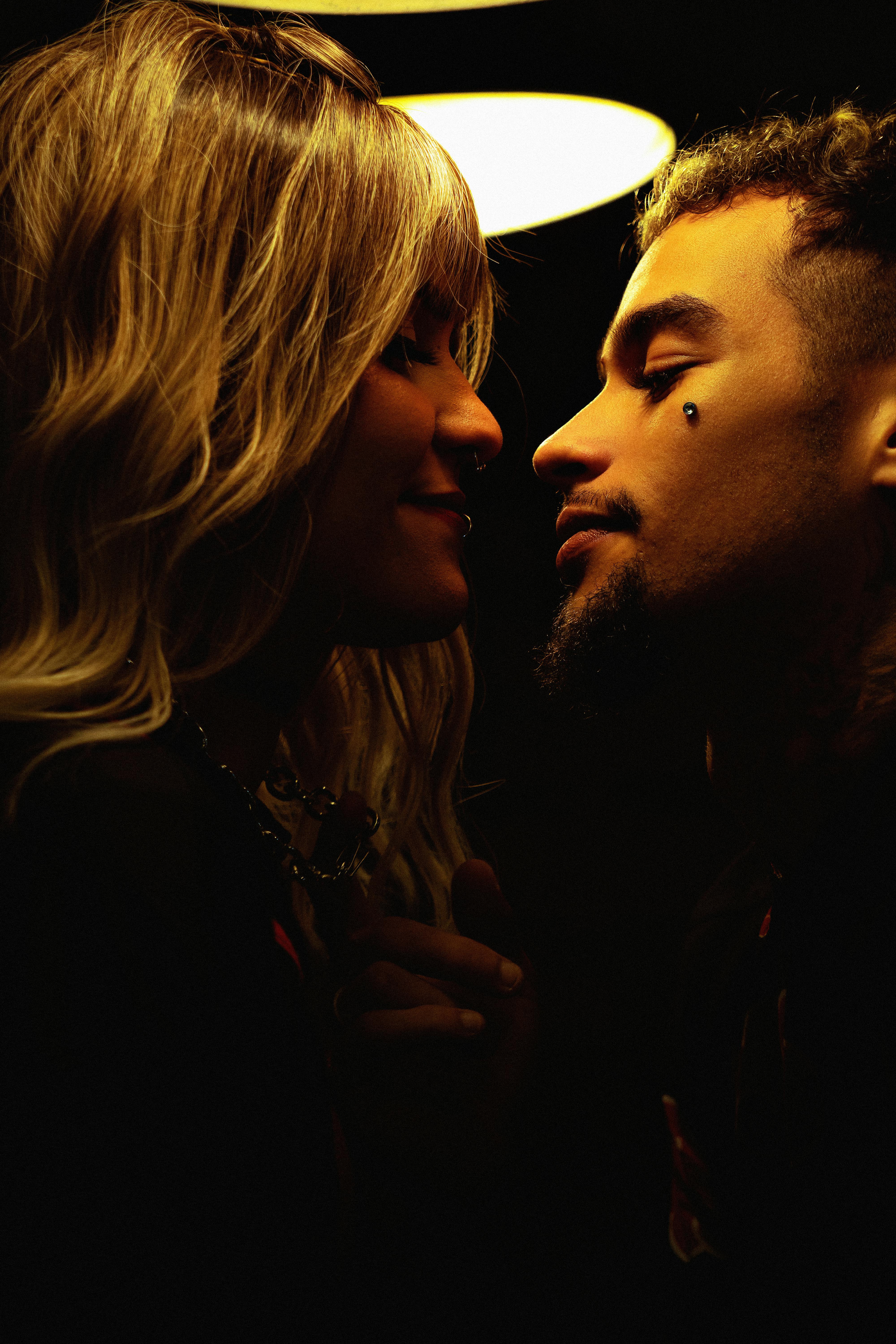Romantic couple sharing a tender moment under warm, intimate lighting indoors.