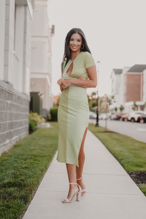 A woman in a green dress is standing on the sidewalk