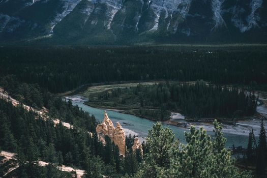 Breathtaking view of Banff National Park's serene river amid lush forests and towering mountains.