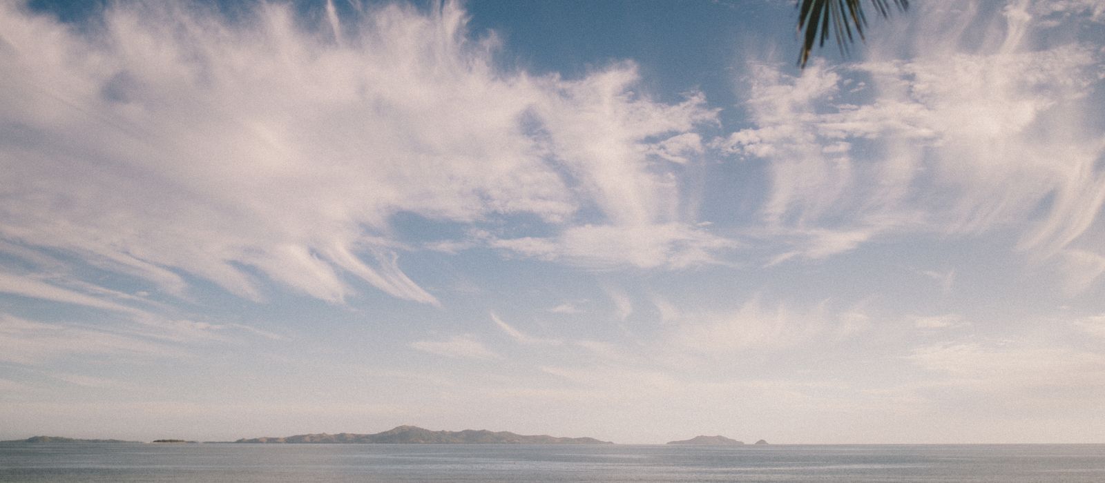 Tranquil ocean scene at Nadi, Fiji with striking clouds and gentle waves. — flights from Cairns to Nadi