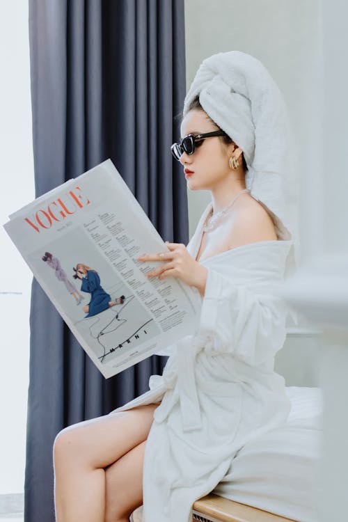 Free A woman in a bathrobe reading a magazine Stock Photo