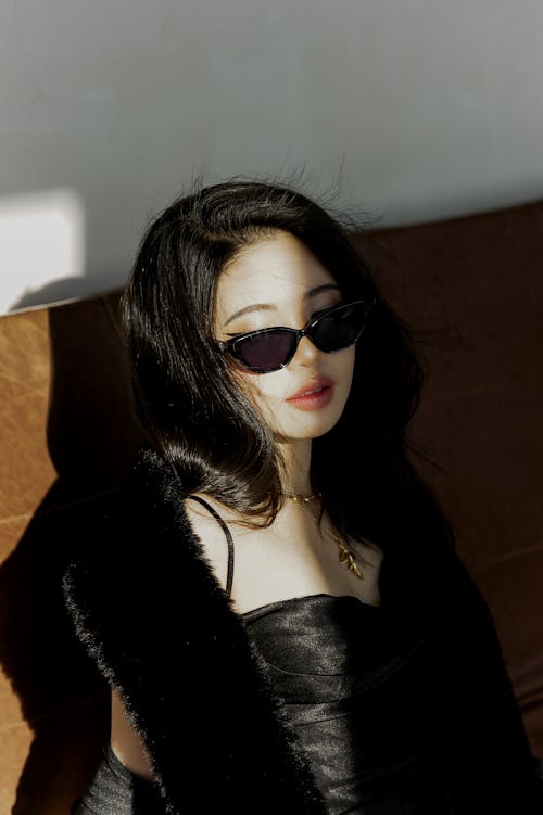 A woman in a black dress and sunglasses