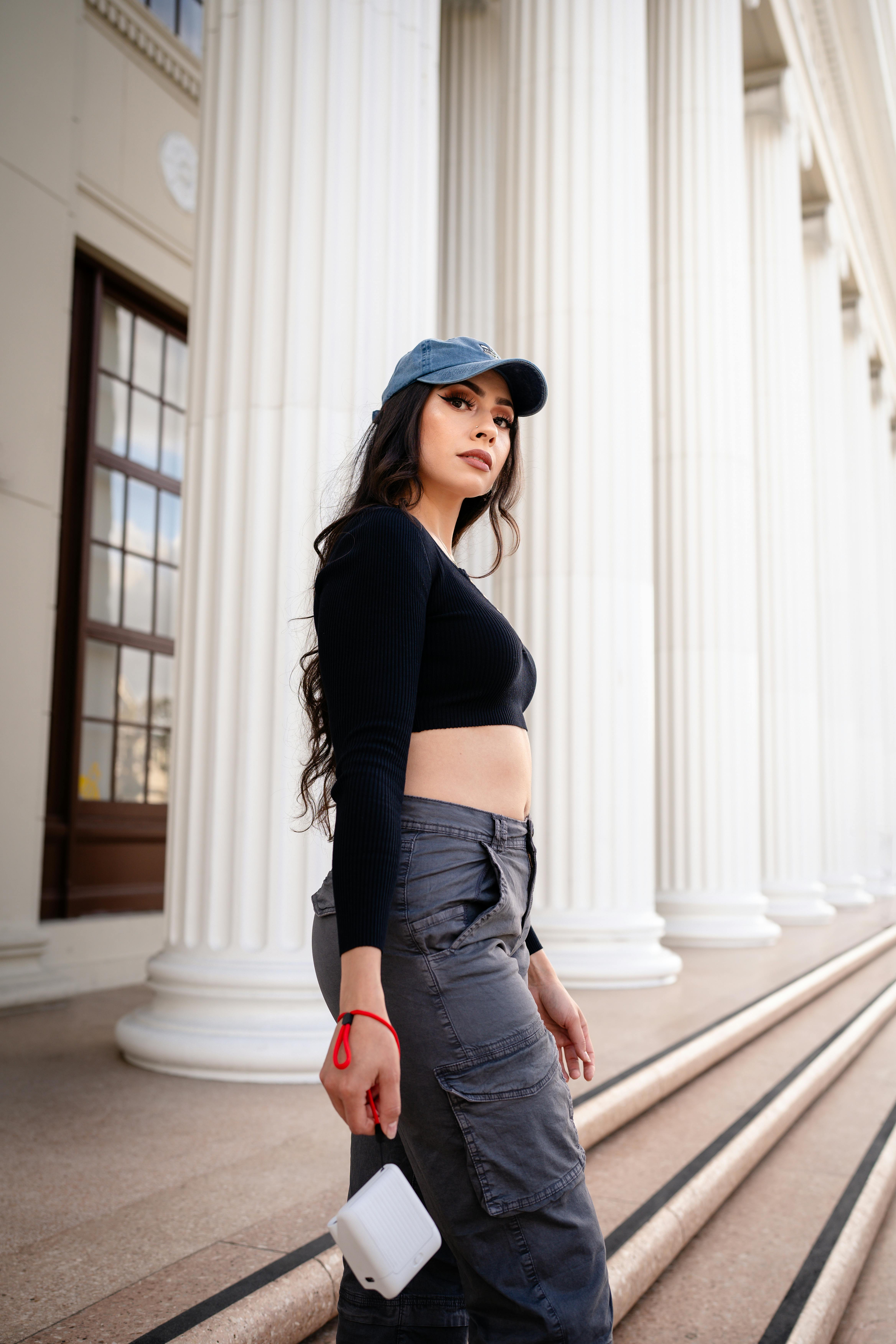 young woman in a casual trendy outfit posing by the alameda high school building