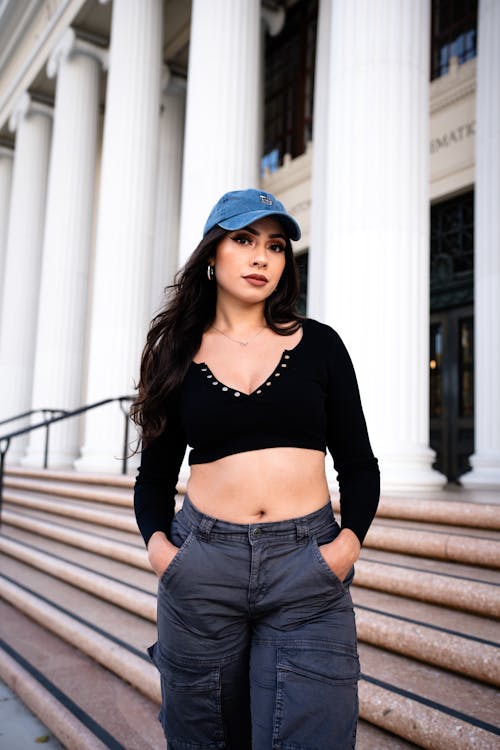 A woman in a crop top and pants standing on steps