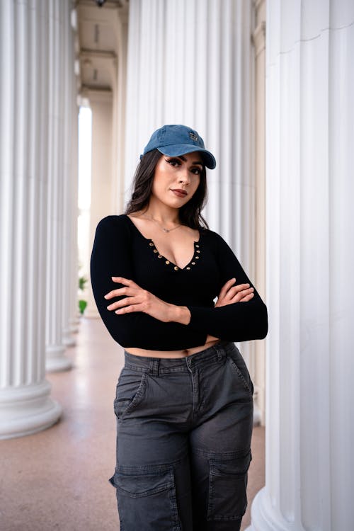 A woman in a cap and pants standing in front of columns