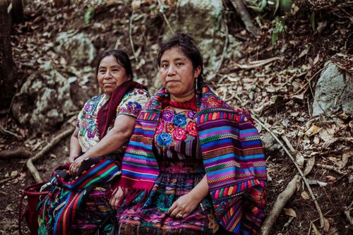 Free Two women in colorful traditional dresses seated outdoors in nature. Stock Photo